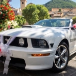 Ford Mustang GT cabriolet blanche décorée de tulle et rubans roses dans un village provençal pour un mariage dans les Alpilles