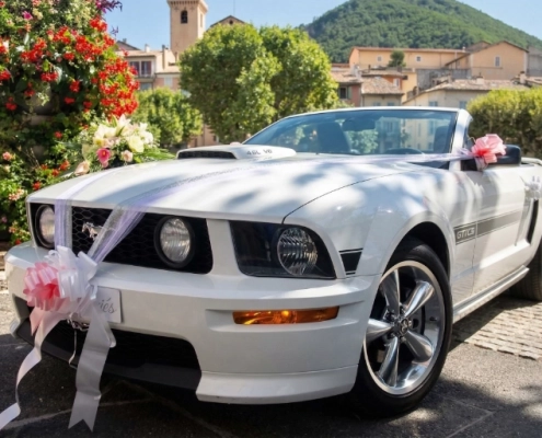 Ford Mustang GT cabriolet blanche décorée de tulle et rubans roses dans un village provençal pour un mariage dans les Alpilles