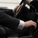 Chauffeur de taxi en costume au volant de sa berline, conduite soignée pour un transfert au tarif fixe vers Arles