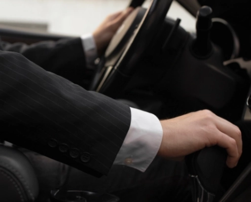 Chauffeur de taxi en costume au volant de sa berline, conduite soignée pour un transfert au tarif fixe vers Arles