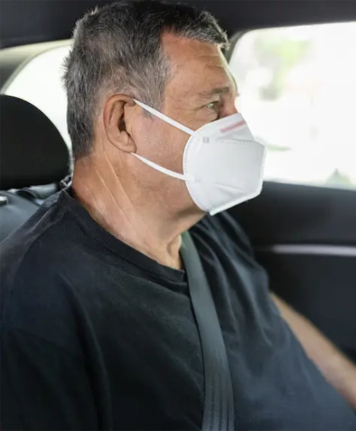 Patient portant un masque sanitaire à l'arrière d'un taxi conventionné CPAM, transport médical vers un centre de soins à Marseille