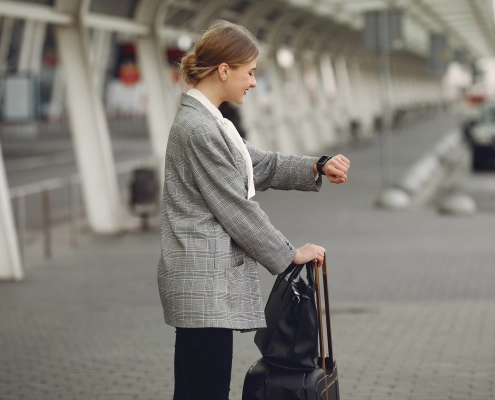 Voyageuse consultant sa montre en attendant son taxi réservé en ligne, confirmation rapide avec réponse directe du chauffeur en Provence