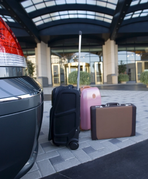 Valises de voyage déposées derrière une berline noire avant un transfert taxi depuis l'aéroport Marseille Provence