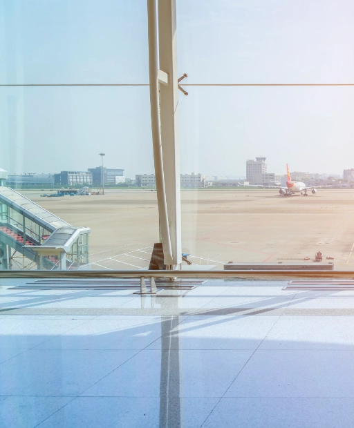 Hall vitré du terminal de l'aéroport Marseille Provence avec vue sur le tarmac et un avion au sol, point d'accueil taxi