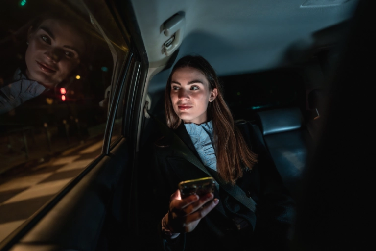 Passagère consultant son téléphone à l'arrière d'un taxi de nuit après un transfert depuis l'aéroport Marseille Provence